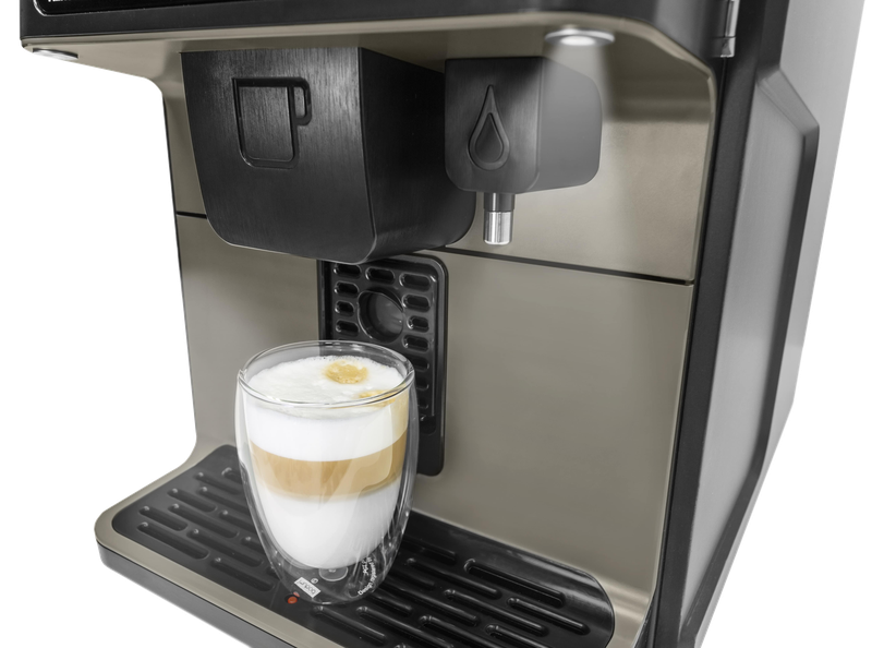 Caffe latte i glas under kaffemaskinens udløb